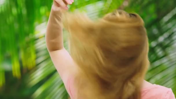Όμορφη ξανθιά γυναίκα αγγίζει τα μαλλιά στη φύση. πίσω όψη. έννοια θεραπεία μαλλιών — Αρχείο Βίντεο