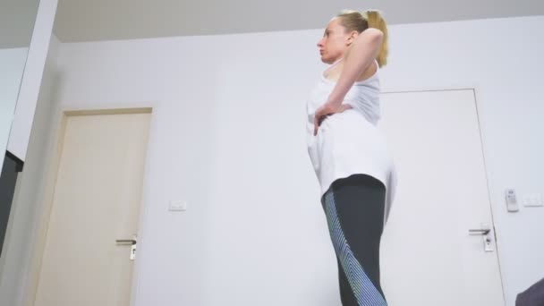 Kvinnan sträcker sig nära spegeln på hennes lägenhet. Konceptet med en hälsosam livsstil, inte en professionell sport. — Stockvideo