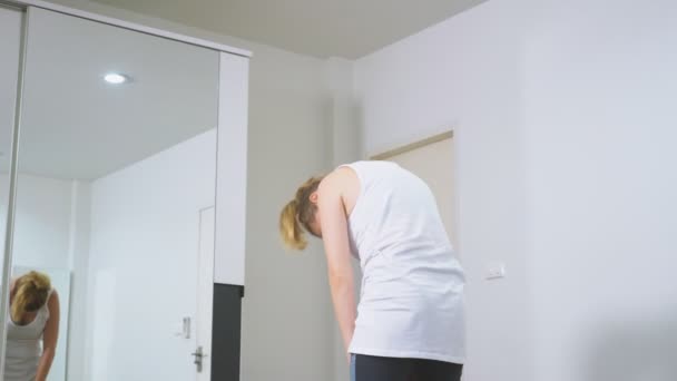 Mulher que se estende perto do espelho em seu apartamento. O conceito de um estilo de vida saudável, não um esporte profissional . — Vídeo de Stock