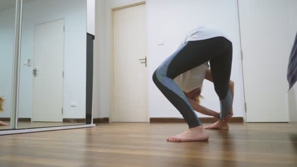 Mujer estirándose cerca del espejo en su apartamento. El concepto de un estilo de vida saludable, no un deporte profesional . — Vídeos de Stock