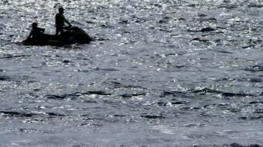 siluet, bir adam bir motosiklet üzerinde denizde yüzen.