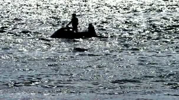 Sylwetka, mężczyzn na motocyklu unosi się nad morzem. — Wideo stockowe