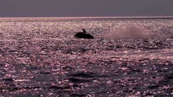 Silhouette, un homme sur une moto flotte sur la mer . — Video