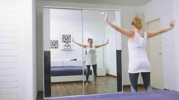 Woman stretching near mirror at her apartment. The concept of a healthy lifestyle, not a professional sport. — Stock Video