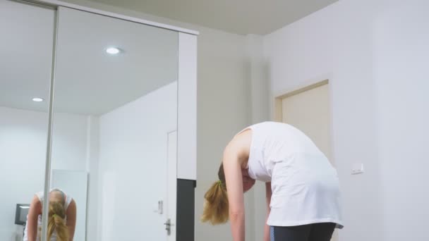 Mujer estirándose cerca del espejo en su apartamento. El concepto de un estilo de vida saludable, no un deporte profesional . — Vídeo de stock