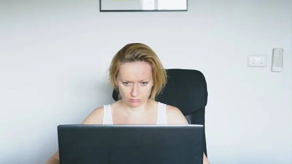 Una mujer que usa un portátil se sienta a la mesa, siente desesperación y comienza a llorar. Emociones humanas. Adicción a Internet . —  Fotos de Stock