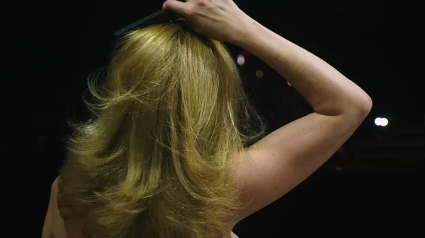 Primer plano, una mujer toca su cabello, en el contexto de la ciudad nocturna. concepto de salud capilar — Foto de Stock