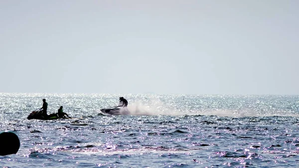 Silueta, un hombre en una moto flota en el mar . — Foto de Stock