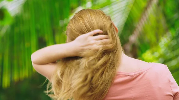 Beautiful blond woman touches her hair in nature. back view. hair treatment concept — Stock Photo, Image