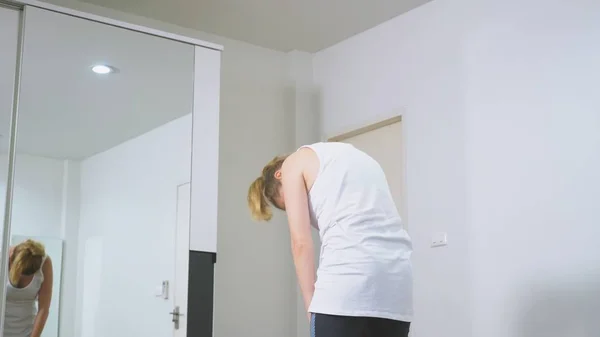 Mujer estirándose cerca del espejo en su apartamento. El concepto de un estilo de vida saludable, no un deporte profesional . —  Fotos de Stock