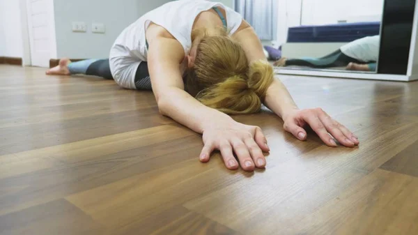 Vrouw die zich uitstrekt in de buurt van spiegel in haar appartement. Het concept van een gezonde levensstijl, niet een professionele sport. — Stockfoto