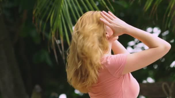 Hermosa mujer rubia toca su cabello en la naturaleza. Vista trasera. concepto de tratamiento capilar — Vídeo de stock