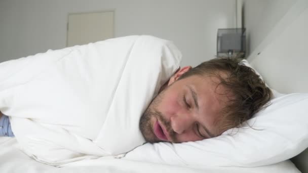 Beteg fiatal ember alszik az ágyban, egy takaró alá tartozó láz — Stock videók