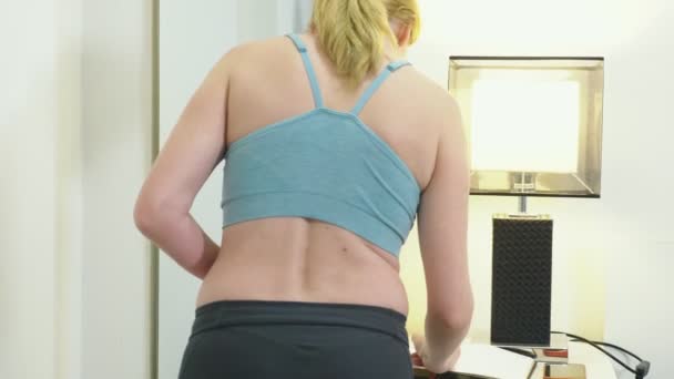 Het concept van overgewicht en gewichtsverlies. Een vrouw meet zelf met een meetlint in de slaapkamer. Kijken naar zichzelf in de spiegel — Stockvideo