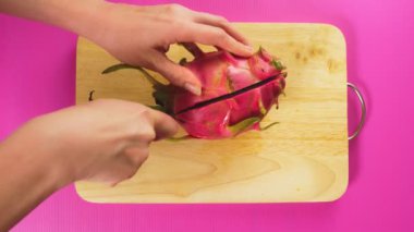 üstten görünüm, el meyve bir tahta masa, beyaz ejderha üzerinde bir bıçakla meyve keser. Doğal sağlıklı gıda kavramı.