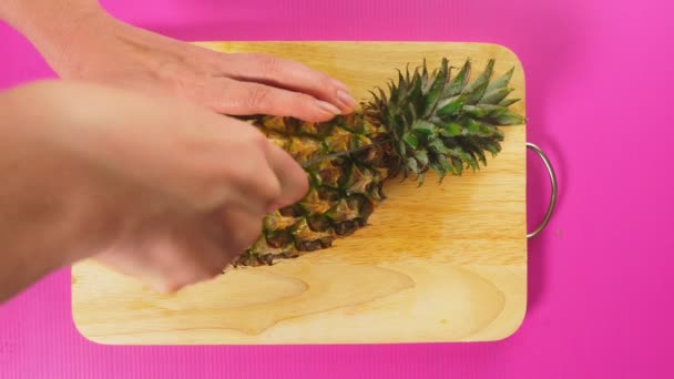 Vista superior, a mão feminina corta a fruta com uma faca em uma tábua de madeira, abacaxi. O conceito de comida saudável natural . — Vídeo de Stock