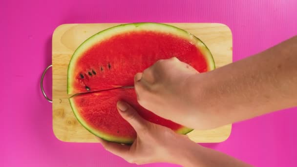 Üstten görünüm, el ile bir bıçak bir tahta masa, kırmızı karpuz üzerinde meyve keser. Doğal sağlıklı gıda kavramı. — Stok video