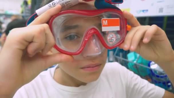 Portrait d'un adolescent heureux qui mesure le masque pour la plongée sous-marine dans le magasin . — Video