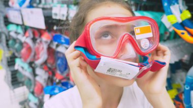Portrait of a happy teenage who measures the mask for scuba diving in the store. clipart