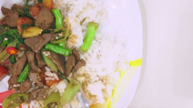 Birisi bir çatal, karaciğer ile pirinç, beyaz bir tabak üstten görünüm yemek yiyor.