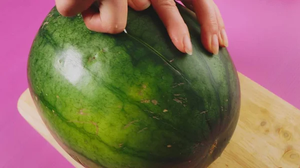 Vista superior, la mano femenina corta fruta con un cuchillo en una tabla de madera, sandía roja. El concepto de comida saludable natural . — Foto de Stock