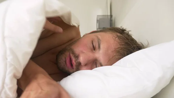 Joven enfermo con fiebre dormido en la cama, cubierto por una manta — Foto de Stock