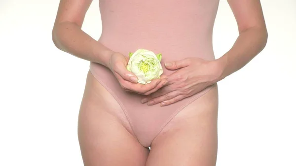 Крупный план беременной женщины, держащей белый цветок лотоса рядом с животом — стоковое фото