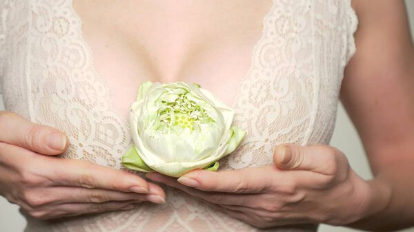 close-up. female breast closeup with lotus flower in her hands. female breast health concept
