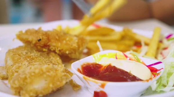 Någon äter snabbmat, friterad krispig och kryddig remsor och pommes frites med salt och ketchup sås. Visa från ovan. — Stockfoto