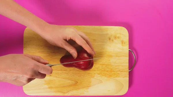 Vista superior, a mão feminina corta um fruto com uma faca em uma tábua de madeira, aumentou a maçã, chompu. O conceito de comida saudável natural . — Fotografia de Stock