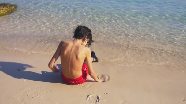 Adolescente ragazzo costruzione castello di sabbia sulla spiaggia tropicale — Video Stock