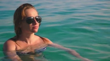 Sarışın kız mayo ve siyah güneş gözlüğü. Seksi vücut ile güzel model mavi deniz suda yüzüyor