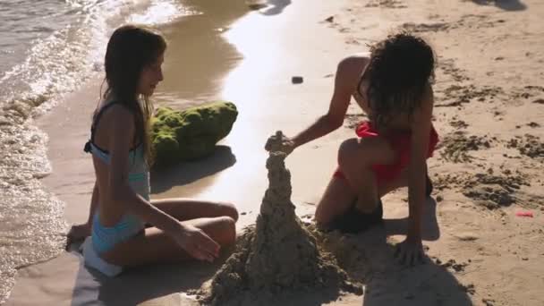 Gençler, kız ve erkek kardeşim tropikal bir plajda kumdan kale yapma — Stok video