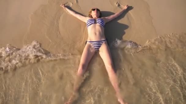 Szőke lány a fürdőruhát és fekete napszemüveg, egy fehér homokos strand az óceán nyaralni. Szexi test gyönyörű modell úszik a víz kék tenger