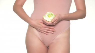 Karnının yanındaki beyaz lotus çiçeği tutan bir hamile kadın Close-up