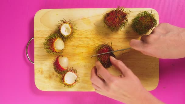 Bovenaanzicht, mannelijke handen verspreid ramboetan op een houten bord. Het concept van natuurlijke gezonde voeding. — Stockvideo