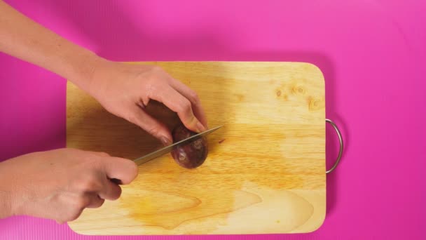 Ovanifrån, kvinnlig hand skär frukt med en kniv på en träskiva, maracuya. Begreppet naturligt hälsosam mat. — Stockvideo