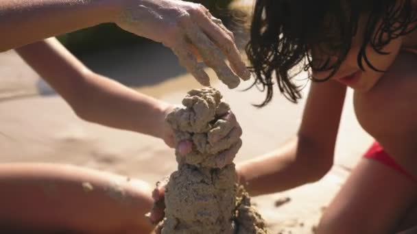 Gençler, kız ve erkek kardeşim tropikal bir plajda kumdan kale yapma — Stok video
