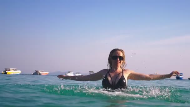 The girl the blonde in a black bathing suit and black glasses. Beautiful model with sexy body is having fun in crystal clear sea water. — Stock Video