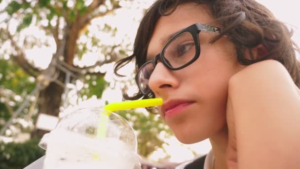 Устал от жары мальчик-подросток пьет холодный коктейль через соломинку, крупным планом — стоковое видео