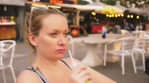 Устал от жары девушка пьет холодный коктейль через соломинку, крупным планом — стоковое видео