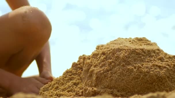Menina constrói um castelo de areia em uma praia tropical. close-up — Vídeo de Stock