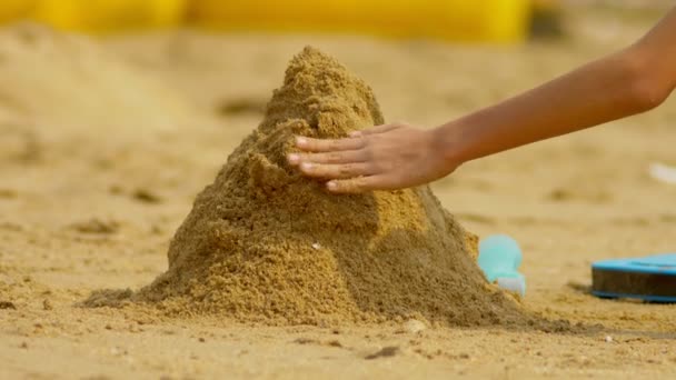 Meisje bouwt een zandkasteel op een tropisch strand. Close-up — Stockvideo