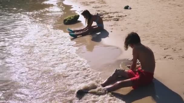 Tieners, broer en zus maken een zandkasteel op een tropisch strand — Stockvideo