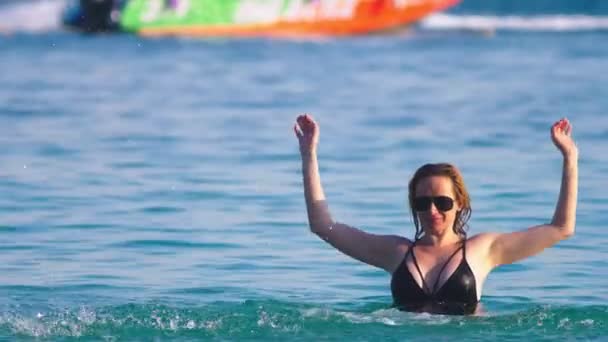 The girl the blonde in a black bathing suit and black glasses. Beautiful model with sexy body is having fun in crystal clear sea water. — Stock Video