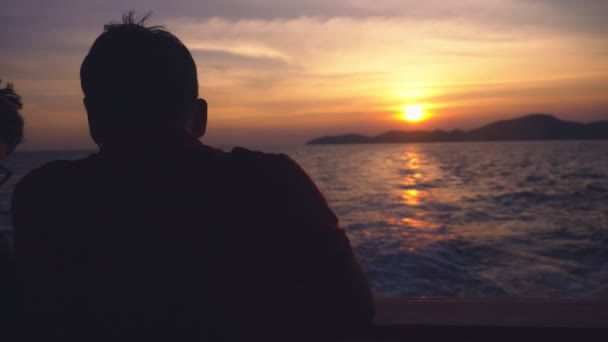 Silueta de un hombre en un barco. vista desde el mar a la isla al atardecer, paisaje marino — Vídeos de Stock