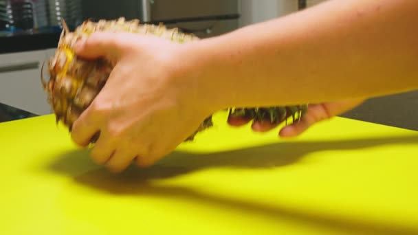 Ovanifrån, kvinnlig hand skär frukten med en kniv på en träskiva, ananas. Begreppet naturligt hälsosam mat. — Stockvideo