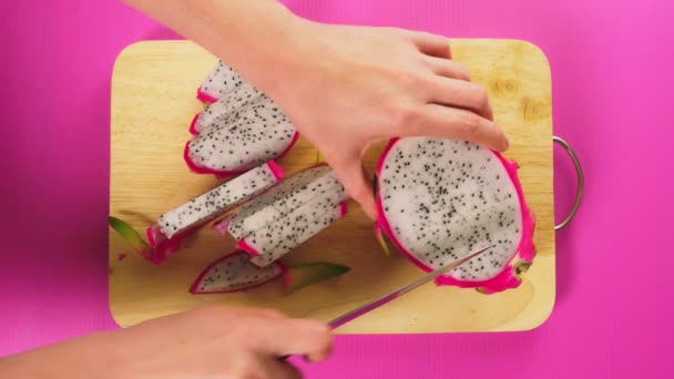 Top view, female hand cuts the fruit with a knife on a wooden board, white dragon fruit. The concept of natural healthy food. — Stock Video