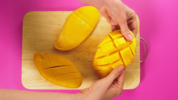 Vue de dessus, main féminine coupe des fruits avec un couteau sur une planche en bois, mangue. Le concept d'aliments naturels sains . — Video