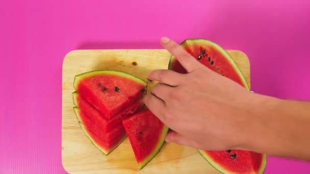 Üstten görünüm, el ile bir bıçak bir tahta masa, kırmızı karpuz üzerinde meyve keser. Doğal sağlıklı gıda kavramı. — Stok video